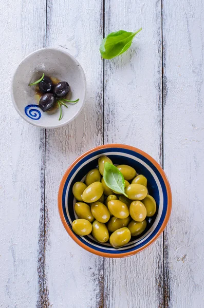 Assortment of olives with herb and sea salt on white wooden background