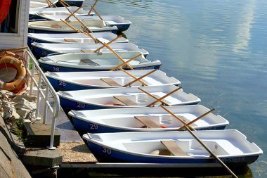 Tekne istasyonunun rıhtımında tekneler. Gökyüzü ve bulutlar suya yansıyor.