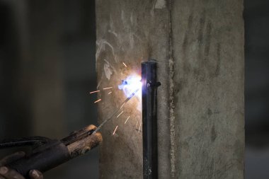 Metal kaynak yapan, duman çıkaran ve kıvılcım çıkaran işçilerin görüntüsü.