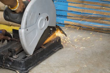 Kesmek için dairesel bıçaklı sürgülü demir testeresi kullanan bir işçi görüntüsü