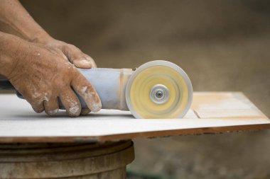 Beyaz kiremit kesmek için araç kullanan işçinin resmi.