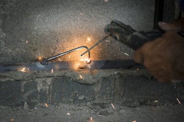 Metal kaynak yapan, duman çıkaran ve kıvılcım çıkaran işçilerin görüntüsü.