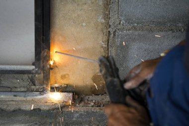 Metal kaynak yapan, duman çıkaran ve kıvılcım çıkaran işçilerin görüntüsü.