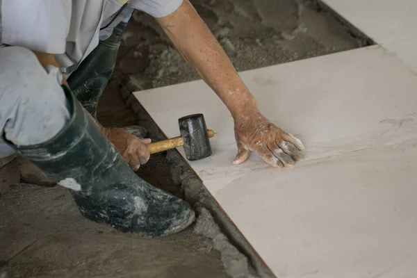 Image of workers are paving the white floor tiles.