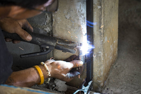 Image of worker welding metal and producing smoke and sparks.