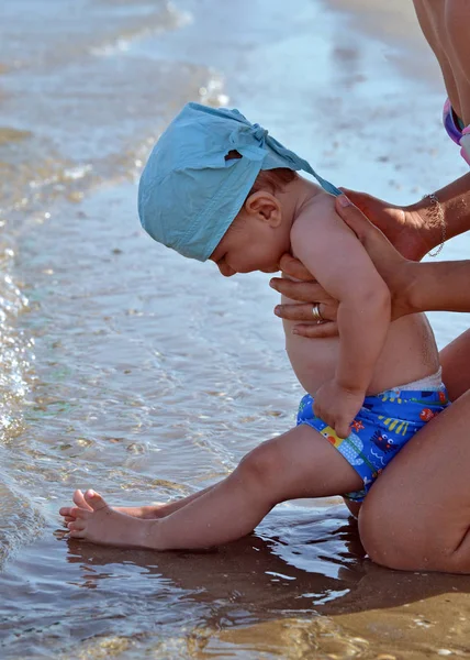 Bebé en la playa tocando agua —  Fotos de Stock