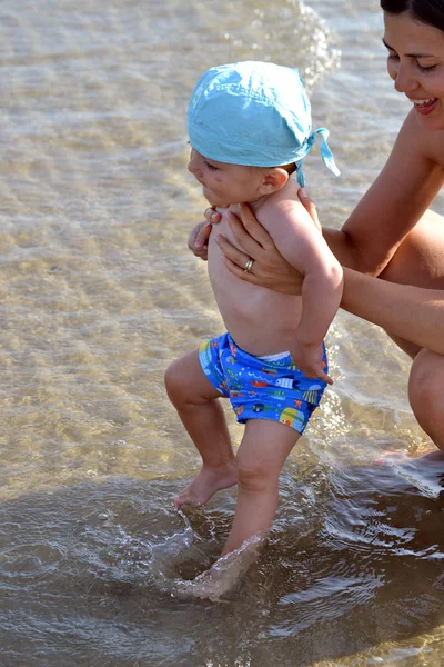 Baby op strand aanraken van water — Stockfoto