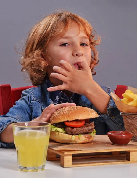 Bambino che mangia patate e hamburger — Foto Stock