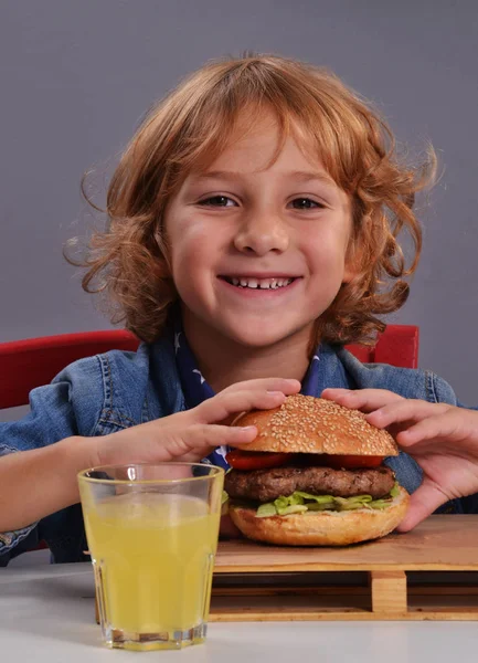 Kid eating potatoes and burger — Stock Photo, Image