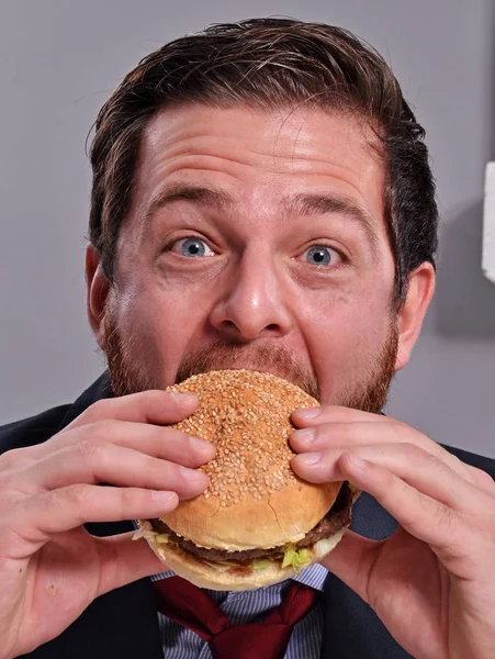 Businessman eating burger — Stock Photo, Image