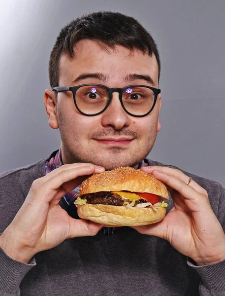 ハンバーガーを食べる表情豊かなオタク — ストック写真