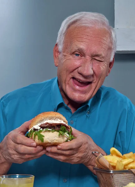 Ανώτερος άνθρωπος με νόστιμο burger — Φωτογραφία Αρχείου