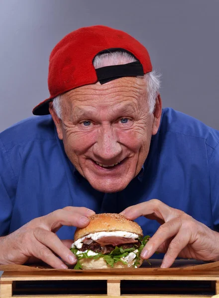 Старший чоловік зі смачним бургер — стокове фото