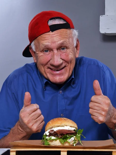 Hombre mayor con sabrosa hamburguesa — Foto de Stock