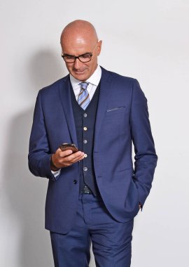 bald middle aged businessman using smartphone on grey background