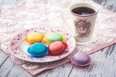 plaka ve kahve peçete ahşap gri masada pembe acıbadem kurabiyesi