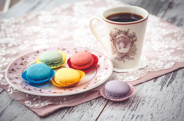 Pink macaroon on plate and coffe on wooden gray table with napkin — Stock Photo, Image