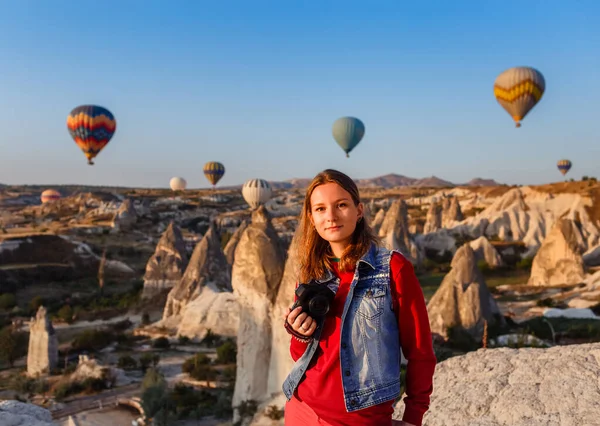  Kapadokya 'da gündoğumunda elinde kamerayla ve sıcak hava balonlarıyla uçan genç ve güzel bir kız fotoğrafçı. Goreme, Kapadokya, Türkiye