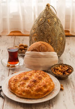 Ramazan 2020 'de COVID-19 virüsüne karşı koruyucu beyaz, tek kullanımlık tıbbi bir maskeyle, çam ve desenli ekmek. Maskedeki ekmeğe odaklan.