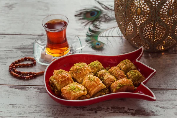 土耳其传统的甜点烘焙在盘子里 其形式是在桌上放郁金香茶 孔雀羽毛 念珠和装饰灯 场深度浅的照片 — 图库照片