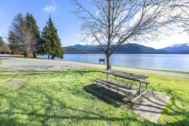 Te Anau, Yeni Zelanda'da göl manzarasına bakan ahşap masa ve sandalye