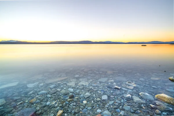 Stenen vid sjön under sunrise — Stockfoto