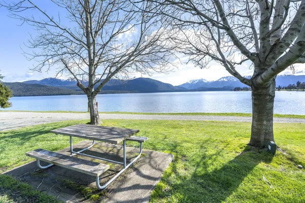 Wooden table and chair facing lake view at Te Anau, New Zealand
