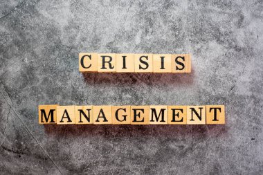 Tahta bloklardaki harfler kara çimento arka planında kriz yönetimi yazıyor..