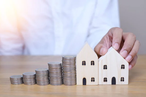 House Model and coins stacks . Save to real estate, property owner get money to home concept, small wooden house model on table with hand stacked coins.