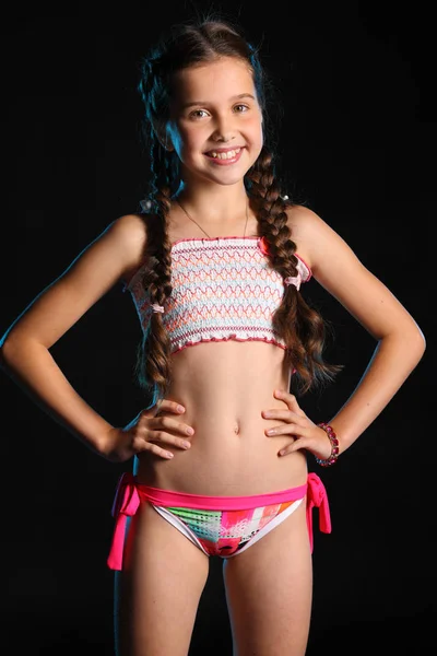 Portrait of a happy young teenage girl in a swimsuit. Pretty child with dark hair and beautiful face adorably smiles. Slender preteen in a bikini. — Stock Image Portrait Happy Young Teenage Girl Swimsuit Pretty Child Dark Hair Royalty Free Stock Photos