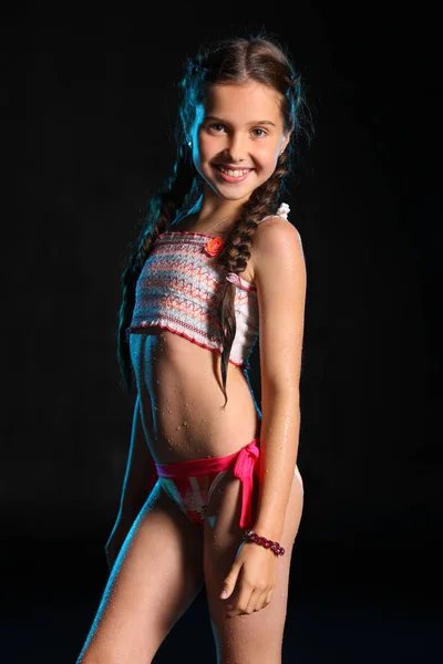 Portrait of a happy young teenage girl in a swimsuit. Pretty child with dark hair and beautiful face adorably smiles. Slender preteen in a bikini. — Stock Image Portrait Happy Young Teenage Girl Swimsuit Pretty Child Dark Hair Stock Picture