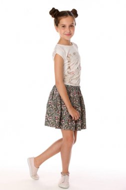 A little girl 12 years old posing in summer clothes. Charming pretty slender young teenager is in a skirt with bare legs. Beautiful brunette child is standing at full length and smiles slightly. clipart