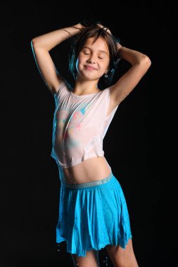 Islak ince gövdeli ayakta büyüleyici bir çocuk portresi. Genç ve güzel güzel kız çıplak karnından ıslak elbise ve etek ile. Çekici genç genç gözleri kapalı ve mutlu.