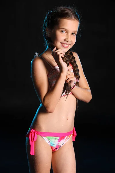 Islak ince gövdeli ayakta büyüleyici bir çocuk portresi. Genç ve güzel güzel kız çıplak göbek ıslak parlak bikini ile. Çekici genç genç gülümseyen ve mutlu.