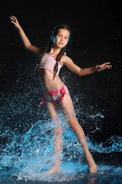 迷人的细长的孩子站在全身上踮起脚尖 漂亮的年轻漂亮的女孩 裸露的腿优雅地摆在湿明亮的比基尼 迷人的年轻少女在水溅 — 图库照片