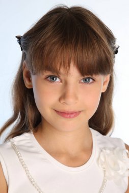 Yakın çekim portre beyaz bir bluz içinde güzel bir kız. Gülümseyen sevimli mutlu çekici çocuk. Genç kız öğrenci 9 yaşında.