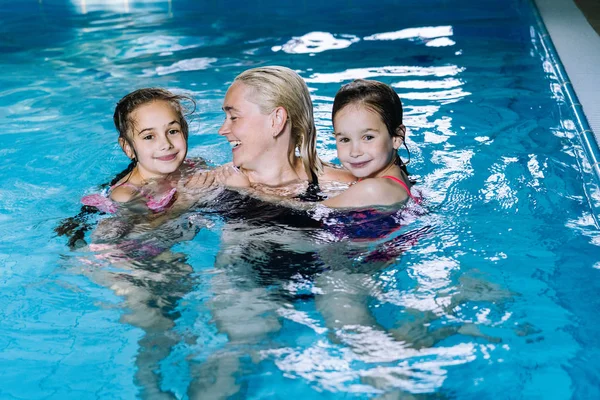 Madre con due figlie che si divertono nella piscina coperta . — Foto Stock