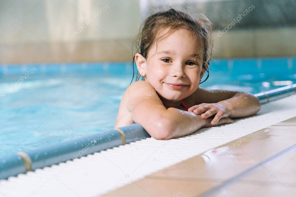 Portrait little girl having fun in indoor swimming-pool.