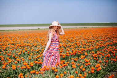 Güzel, uzun, kızıl saçlı, çizgili elbiseli bir kadın.