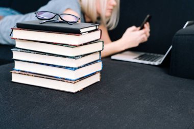 Blond hair Woman lying on black sofa using laptop in living room