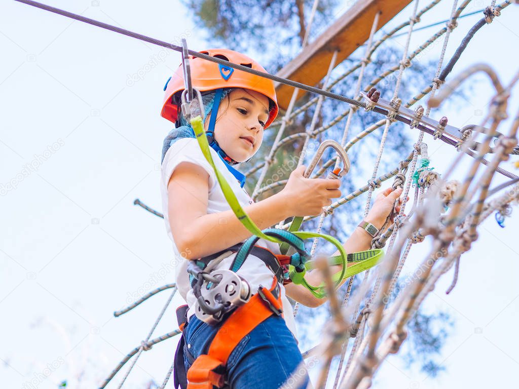 Teenager in orange helmet climbing in trees on forest adventure 