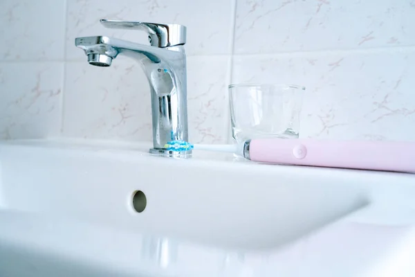 Pink electric toothbrushes and glass in the bathroom at home. — Stock Photo, Image