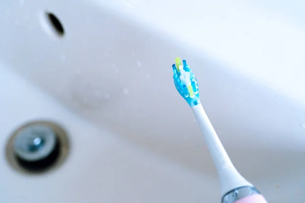 Pink electric toothbrushes and glass in the bathroom at home. — Stock Photo, Image