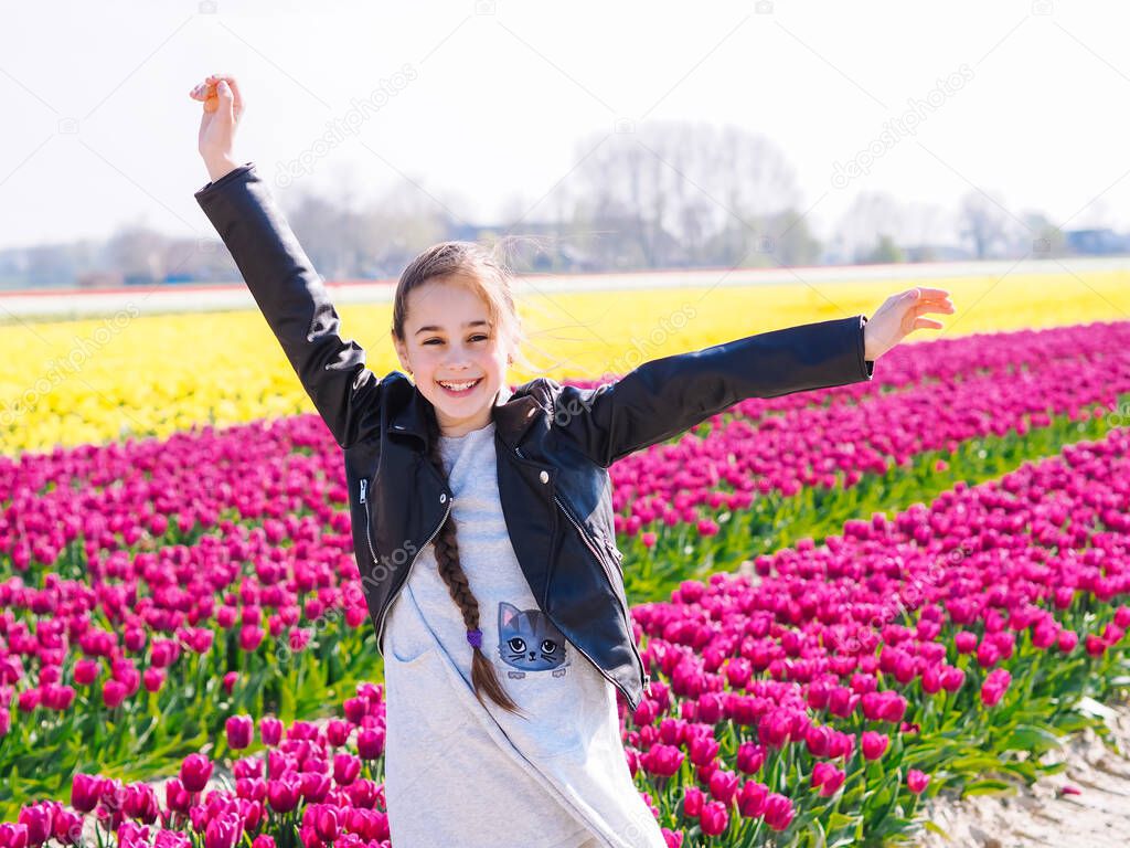 Cute teen girl with long hair smelling tulip flower on tulip fields in Amsterdam region, Holland, Netherlands.