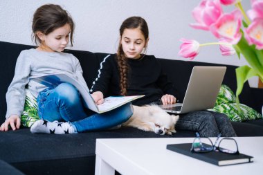 Çevrimiçi eğitim, uzaktan öğrenme, evde eğitim. Evde dijital tablet dizüstü bilgisayar dersinde tıbbi maske takan Childeren ödev çalışıyor. Karantinada sosyal mesafe. Kişisel izolasyon