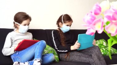 Çevrimiçi eğitim, uzaktan öğrenme, evde eğitim. Medikal maskeli çocuklar evde dijital tablet dizüstü bilgisayar dersinde ödev çalışıyorlar. Karantinada sosyal mesafe. Kişisel izolasyon.