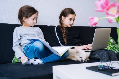 Çevrimiçi eğitim, uzaktan öğrenme, evde eğitim. Evde online ders sırasında ödevlerini yapan çocuklar bilgisayarın tabletinde ve görüntülü arama yapıyorlar. Karantinada sosyal mesafe. Kişisel izolasyon.