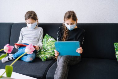 Çevrimiçi eğitim, uzaktan öğrenme, evde eğitim. Evde online ders sırasında ödevlerini yapan çocuklar bilgisayarın tabletinde ve görüntülü arama yapıyorlar. Karantinada sosyal mesafe. Kişisel izolasyon.