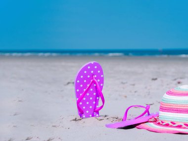 Plaj sezaryenleri plaj terlikleri ve tropikal kumda mavi deniz ve gökyüzü zeminine karşı renkli şapkalar. Yaz tatili konsepti, deniz turu, sıcak güneşli yaz..