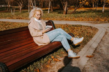 kadın bir parkta bankta bir kitap okuma